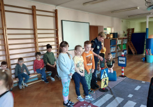 dzieci uczestniczą w zajęciach o bezpieczeństwie na sali gimnastycznej, poruszają się po drodze i po pasach zgodnie z przepisami ruchu drogowego