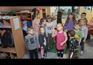 grupa dzieci pozuje do wspólnego zdjęcia z alpakami