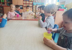 dzieci wykonują eksperymenty wykorzystując wodę, barwniki, cytrynę, sól, cukier, różne przedmioty