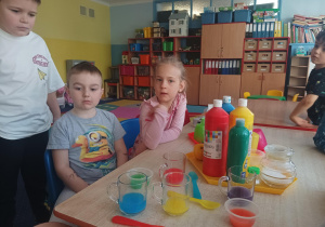 dzieci wykonują eksperymenty wykorzystując wodę, barwniki, cytrynę, sól, cukier, różne przedmioty
