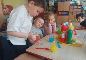 dzieci wykonują eksperymenty wykorzystując wodę, barwniki, cytrynę, sól, cukier, różne przedmioty
