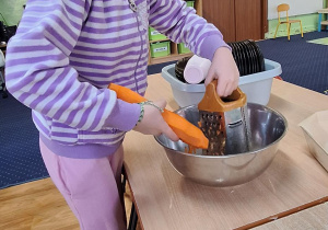 Dziewczynka ściera na tarce marchewkę.