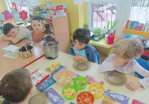 dzieci świętują dzień czekolady, jest fontanna czekoladowa, różne rodzaje czekolady, owoce, galaretka