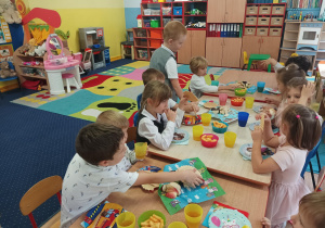dzieci z grupy drugiej siedzą na ławeczce na sali gimnastycznej