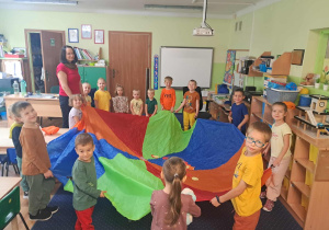 Dzieci bawią się kolorowymi chustkami przy muzyce.