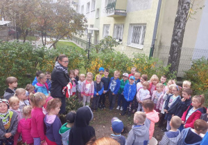 Dzieci zgromadzone w kole na dworze słuchają Pani Irminy w jakim celu się tu zebrały.