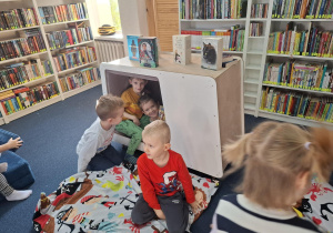 Dzieci siedzą na dywanie w bibliotece.