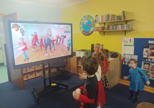 dzieci tańczą do muzyki przed tablicą interaktywną