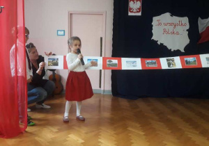 Dziewczynka recytuję wiersz i wskazuje odpowiednią ilustrację.