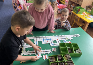 Dzieci przy stolikach kodują drogę ozobota.