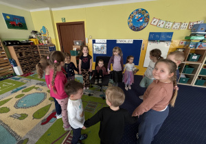 Dzieci ustawione w kole śpiewają "100 lat".