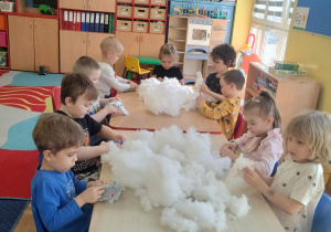 dzieci przy stolikach wykonują i ozdabiają króliki z materiału