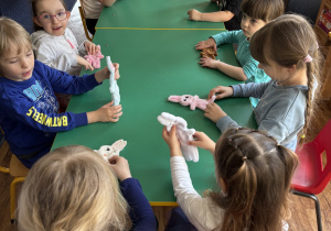 Dzieci siedzą przy stole ze swoimi zajączkami.