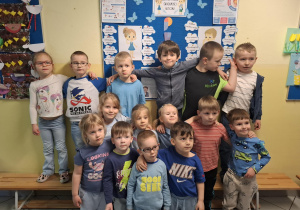 dzieci pozują do zdjęcia na tle tablicy poświęconej zagadnieniom spektrum autyzmu