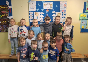 dzieci pozują do zdjęcia na tle tablicy poświęconej zagadnieniom spektrum autyzmu