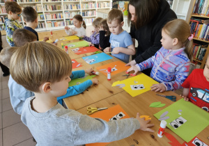Dzieci przy stołach wykonują prace plastyczne.