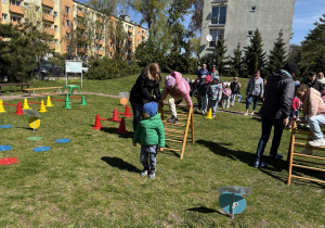 w ogródku przedszkolnym odbywają się sportowe konkurencje, w których uczestniczą dzieci