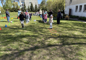 w ogródku przedszkolnym odbywają się sportowe konkurencje, w których uczestniczą dzieci