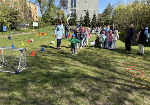 w ogródku przedszkolnym odbywają się sportowe konkurencje, w których uczestniczą dzieci