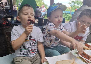 dzieci podczas wycieczki do pasieki w Lipce jedzą kiełbaski
