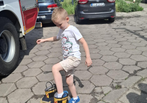 chłopiec przymierza buty strażackie
