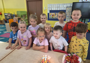 dziewczynka obchodzi urodziny, na stoliku widać tort z cyferką 7