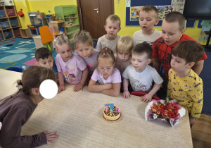 dziewczynka obchodzi urodziny, na stoliku widać tort z cyferką 7