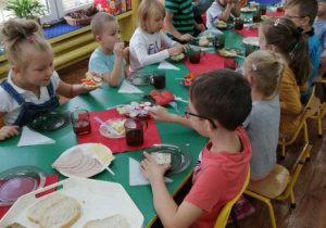 Dzieci siedzą przy stole i rozpoczynają śniadanie.