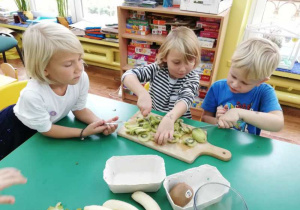 Dziewczynki kroją kiwi na cząstki.