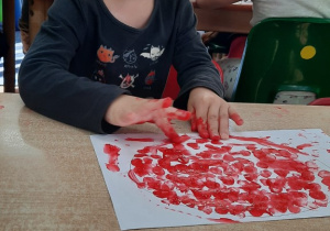 Chłopiec stempluje palcami kształt figury.