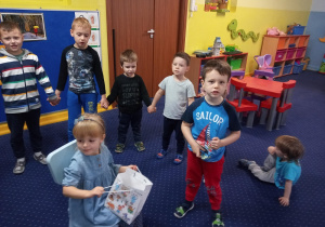 Dziewczynka siedzi na krześle, dzieci składają jej życzenia