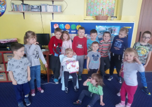 dziewczynka siedzi na krześle dzieci stoją wokół niej