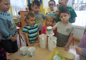 Dzieci stoją przy stoliku i wykonują koktajl