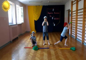 Trzej chłopcy z grupy IV tańczą do piosenki marynistycznej - patrzą przez lunety.
