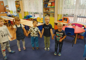 dzieci stoją w półkolu i trzymają się za ręce