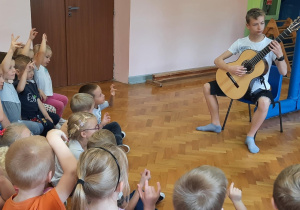 Uczeń szkoły muzyczne gra koncert na gitarze dla dzieci.
