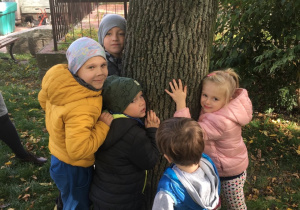 Dzieci przytulają się do drzewa.