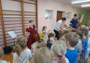 Wszyscy stoją i wykonują ćwiczenia dłoni przygotowujące do gry na instrumencie.