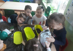 Dziewczynka wsypuje ziemię do doniczki.