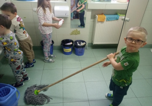chłopiec mopem myję podłogę w łazience