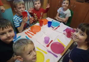 dzieci siedzą przy stole, na którym leży zastawa stołowa