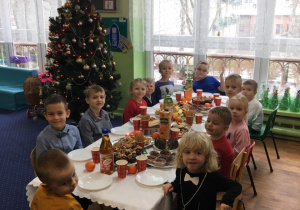 Dzieci siedzą przy wigilijnym stole.