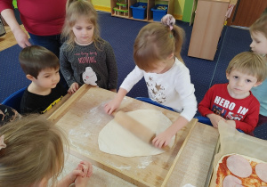 chłopiec wałkuje placek na pizzę