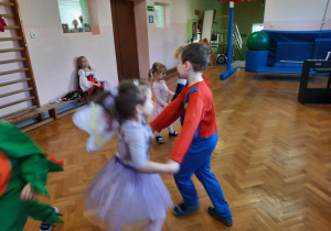 Dziewczynka i chłopiec tańczą w kółeczku.