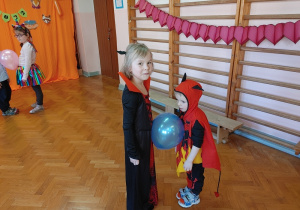 dziewczynka i chłopiec tańczą z balonem