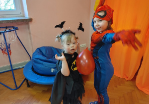dziewczynka i chłopiec tańczą z balonem