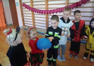 dzieci w kółeczku bawią się przy muzyce i podają sobie balon