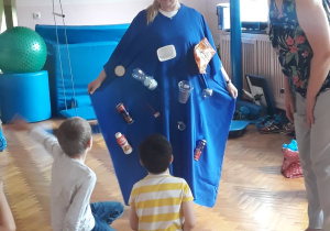 Na sali gimnastycznej pani w stroju Ziemi prezentuje się dzieciom, które siedzą na podłodze.