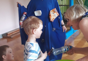 Dzieci wrzucają śmieci do kosza.