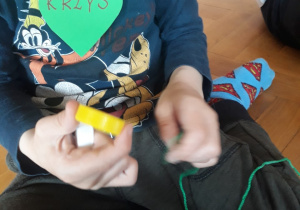 Dziecko nawleka korek na sznurek.